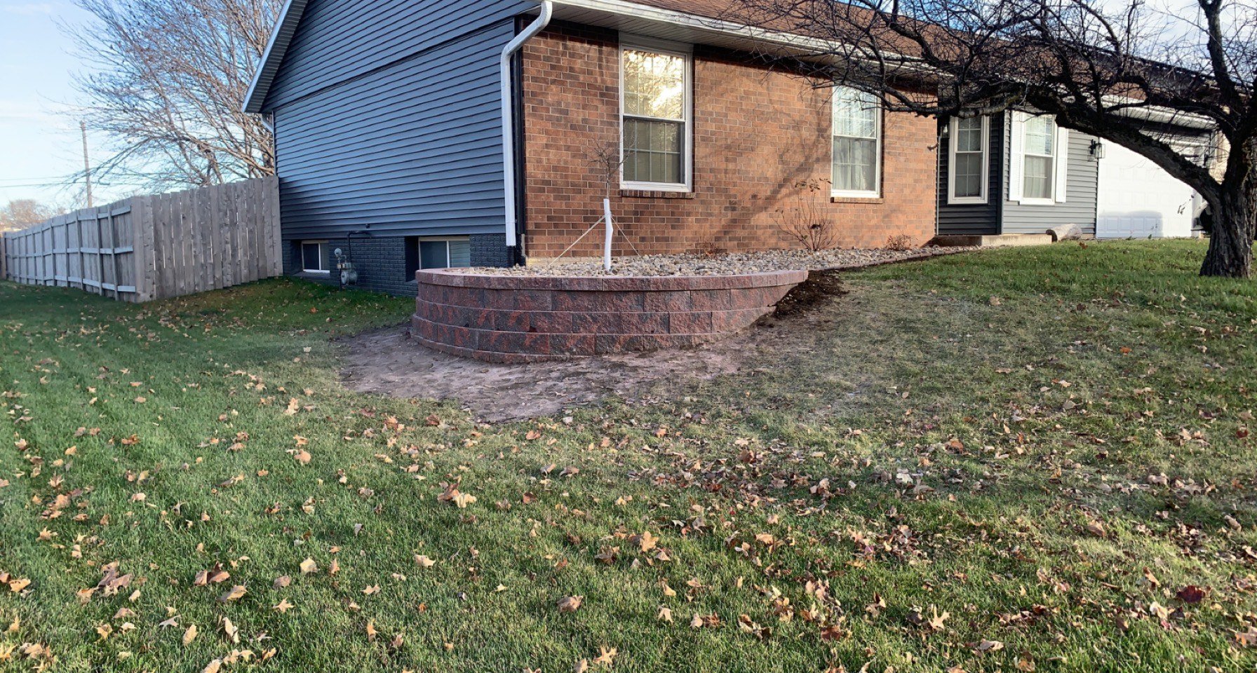 Brick and siding house with fallen autumn leaves on grassy lawn