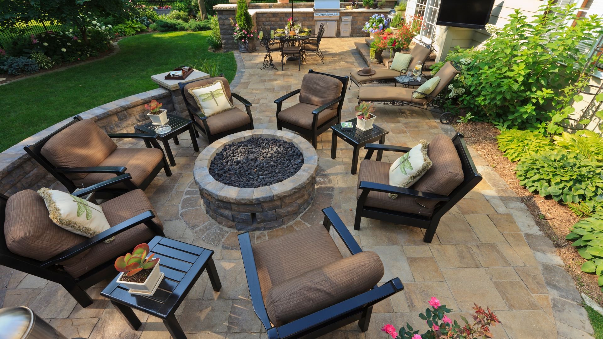 Outdoor patio with stone fire pit, lounge chairs, and landscaped garden